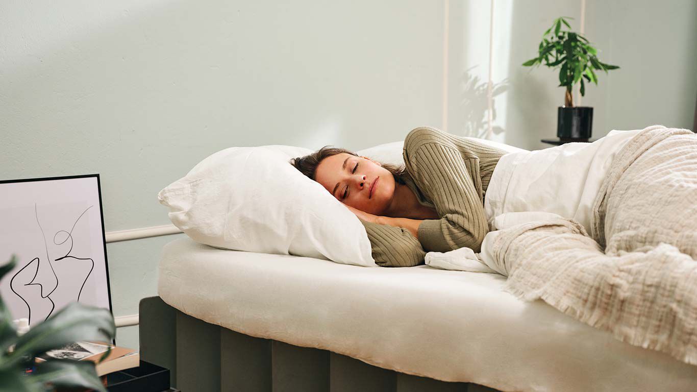 Een vrouw ligt in zijligging in haar bed te slapen.